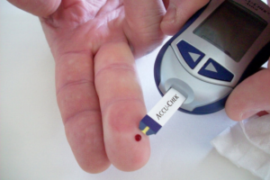A finger with a droplet of blood is used to provide a sample for blood glucose testing; which accompanies a letter written to Diabetes-1 for Dear Diagnosis.