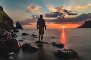 A man looks out over a body of water, as the sunsets; to complement the tone of a letter written to Cancer and published at www.deardiagnosis.com.