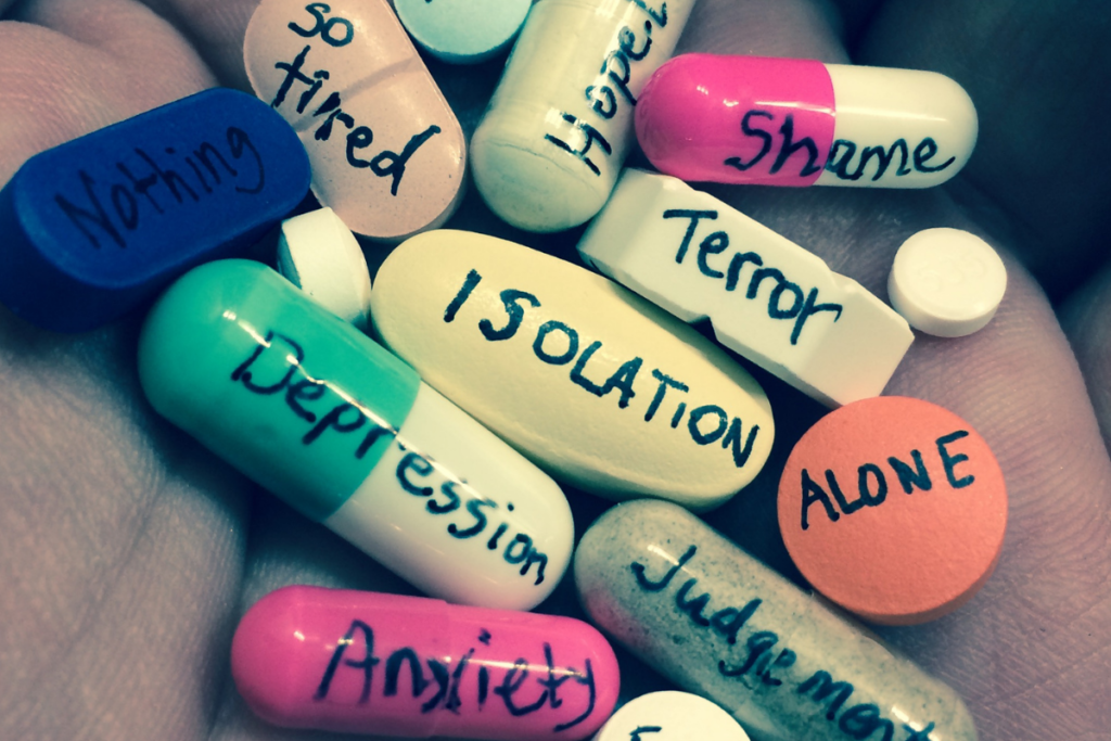 A handful of pills with words written atop each one to convey what it feels like to live with Depression.