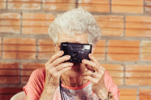 An elderly woman with alzheimer's holding a camera posted to reflect the tone of a letter submitted to the Dear Diagnosis literary project.