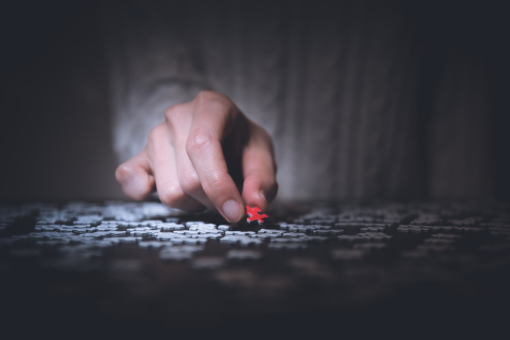 A hand removes a single red puzzle piece from an assortment, which reflects the tone of the corresponding letter written for the Dear Diagnosis project.